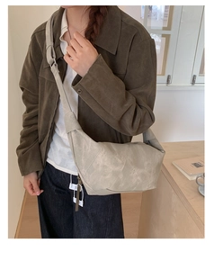 Detail view of large grey suede dumpling bag showing minimalist seams and soft texture