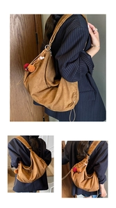 Detail view of large brown suede hobo bag featuring drawstring and colorful pom-poms
