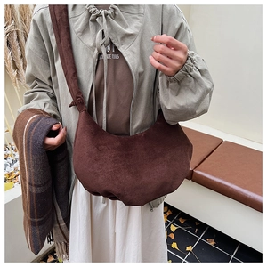 Close-up of a vintage dark brown suede dumpling bag with pleated details and wide strap