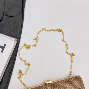 Detailed close-up of a gold evening clutch bag with shimmering rhinestone embellishments