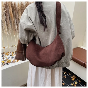 Detail of soft brown suede crescent bag featuring knotted strap and drawstring fold