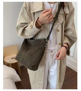 Detail of dark green suede tote bag with slim shoulder strap styled with trench coat