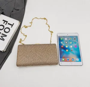 Size comparison of a gold rhinestone clutch bag with chain next to a white tablet