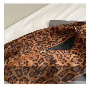 Close-up of sleek silver round zipper hardware on a leopard print tote bag fabric