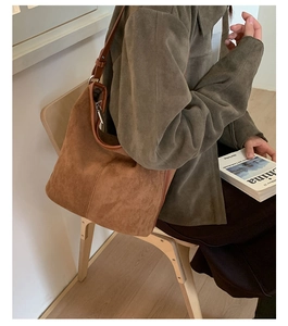 Brown suede hobo bag shown in lifestyle setting with textured fabric and leather trim