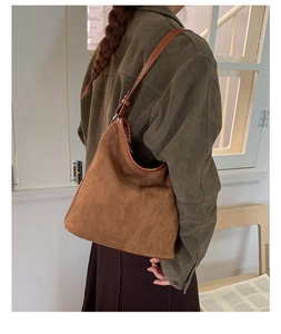 Detail of soft brown suede shoulder bag with vintage texture and adjustable strap