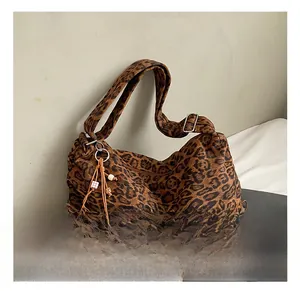 Detailed shot of leopard print tote bag featuring fluffy pom-pom charm and metal buckle