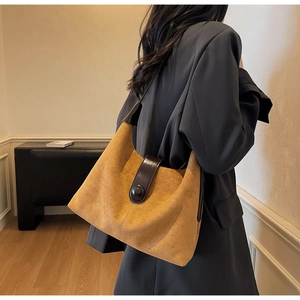 Detailed view of brown suede shoulder bag with polished leather strap on model
