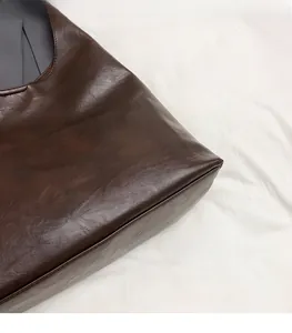 Detailed close-up showing the premium leather texture and stitching of this brown tote bag