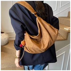 Detailed back view of a brown suede hobo bag with colorful pompom charm and wide strap