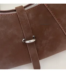 Detail of dark brown suede handbag with silver metal ring and fine stitching