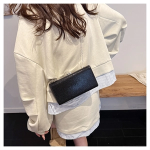 Fashionable black evening clutch bag with glitter texture and silver chain strap