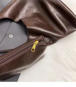 Detail of high-quality golden zipper and textured brown leather on a luxury tote bag