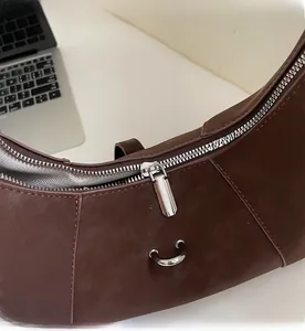 Detail of smooth metal zipper and brown suede crescent bag with silver hardware accents