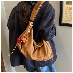 Detail view of brown faux suede hobo bag featuring drawstring pleats and colorful pompoms