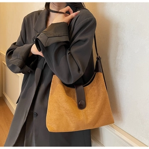 Detail of vintage suede shoulder bag in ginger yellow with dark brown leather straps