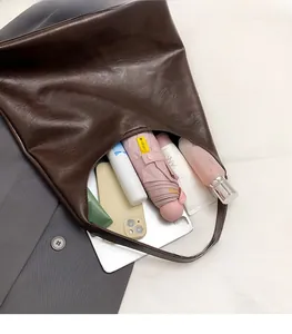 Macro shot showing the spacious interior of a dark brown vintage tote bag with daily items