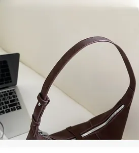 Detail of adjustable strap and silver zipper on brown retro leather hobo shoulder bag
