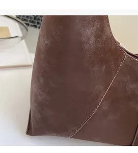 Close-up of brown suede shoulder bag showing soft matte texture and fine stitching detail