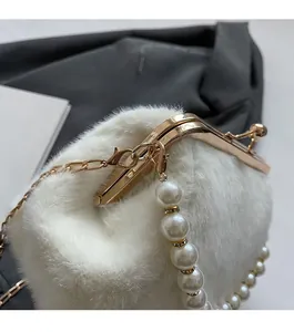 Détail du sac en fausse fourrure blanche avec cadre doré et bandoulière en perles