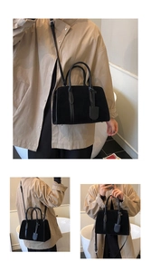 Détail du sac Boston noir en daim avec poignées rondes et bandoulière réglable