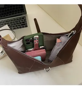 Spacious interior of brown matte hobo bag holding a phone, umbrella, and wallet