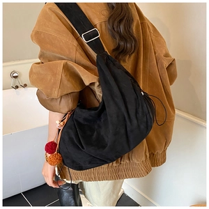 Detail view of a black drawstring shoulder bag with a decorative plush charm accessory