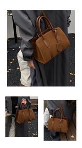 Détail d'un sac Boston en daim marron avec poignées renforcées et fine bandoulière réglable