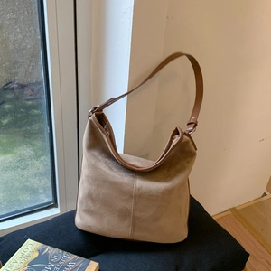 Detail of light khaki suede hobo bag with brown leather handle and zipper closure