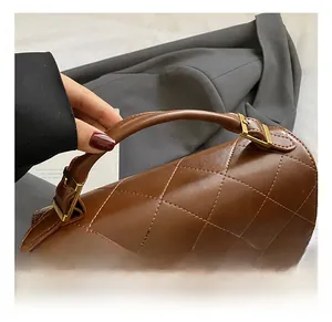 Gros plan sur un sac en cuir matelassé marron avec boucle dorée et poignée épaisse