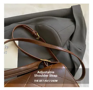 Détail de la bandoulière réglable et boucle en métal doré mat sur un sac matelassé marron