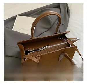 Gros plan sur un sac Boston en daim marron avec détails de fermeture éclair argentée