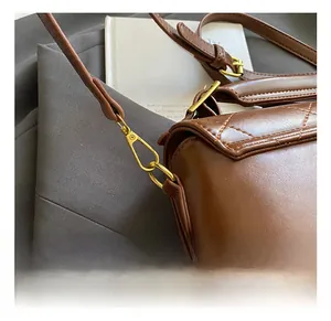 Détail du crochet pivotant doré et des surpiqûres sur le sac matelassé marron