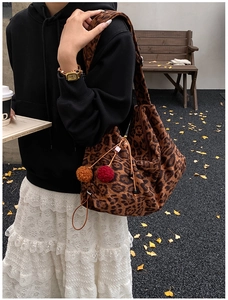 Chic leopard print tote bag with red and brown fur ball charms in autumn street scene