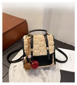 Detail view of mini backpack featuring beige plush flap with embossed heart patterns
