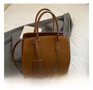 Détail des coutures en daim marron et cuir lisse sur un sac à main bandoulière chic