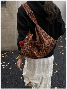 Detailed view of retro leopard print crossbody slouchy bag with drawstring and pompom.