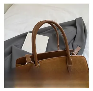 Détail du sac cabas rétro en cuir mat marron foncé avec ses anses cylindriques élégantes