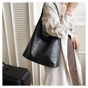 Minimalist black tote bag in soft leather texture shown on shoulder for a slouchy look