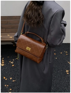 Détail du sac matelassé marron foncé avec fermoir doré et texture de poignée en cuir