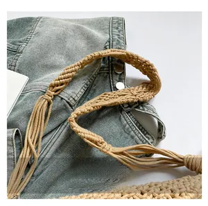 Detail of light brown handcrafted spiral woven shoulder strap on blue denim jacket