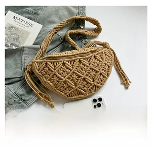 Detail of handmade hollow-out straw bag with tassels and shoulder strap shown with phone