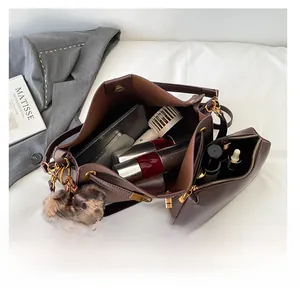 Detail of dark brown leather tote bag interior with matching pouch and leopard pompom