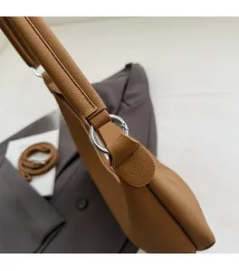 Détail de la texture en cuir marron caramel et des ferrures en anneau métallique argenté