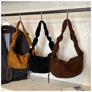 Three crescent shoulder bags in yellow, black, and brown with pleated strap details