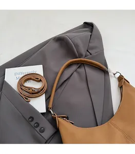 Gros plan du sac demi-lune en similicuir marron avec texture grainée élégante sur blazer