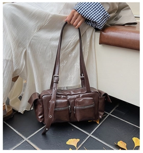 Detail of dark brown vintage faux leather shoulder bag with functional zip pockets