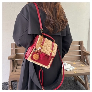 Detail of red leather and beige fleece crossbody bag with plush charms on a model