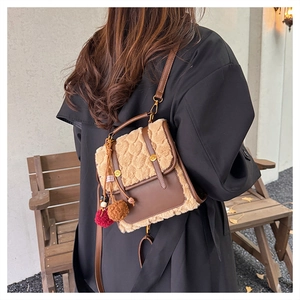 Detail of a brown PU leather crossbody bag with heart embossed plush texture and charms