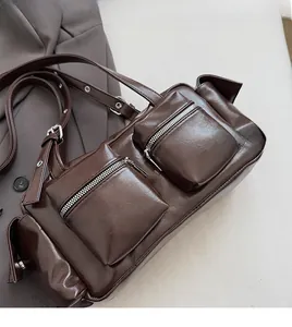 Macro shot of dark brown multi-pocket shoulder bag with metal zippers and adjustable strap